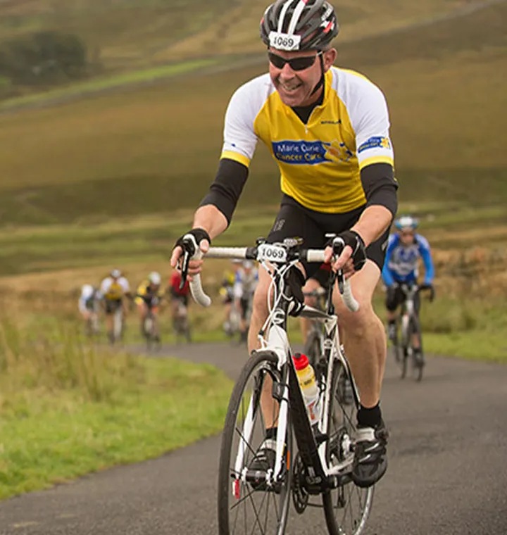 A cyclist in Marie Curie kit on a charity bike ride